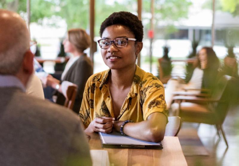 photo of young Black person with glasses at a table with another person